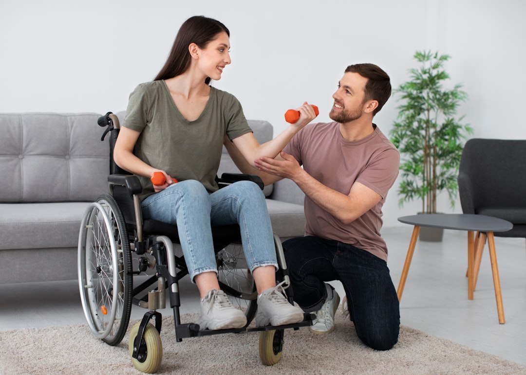 Patiente en fauteuil roulant faisant des exercices avec des haltères, accompagnée par un physiothérapeute