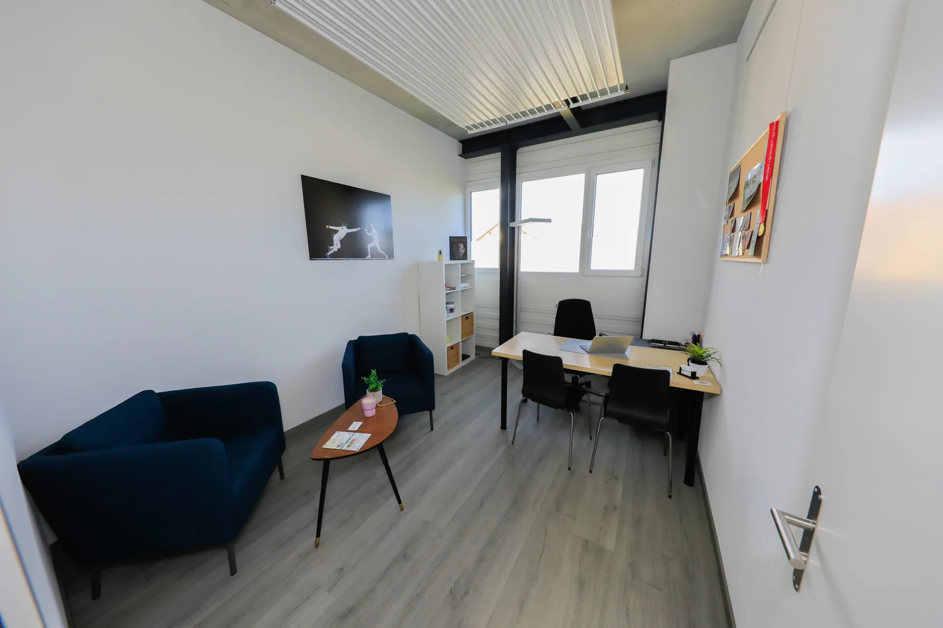 Bureau de consultation du centre VO2Sport avec un espace salon, un bureau et des chaises face aux fenêtres.