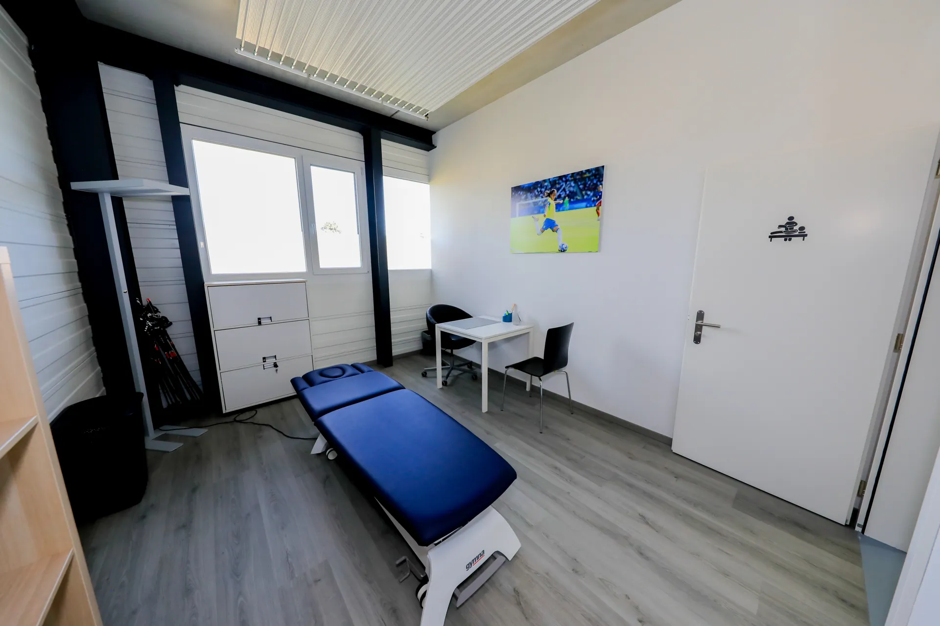 Cabinet de massothérapie du centre VO2Sport avec table de massage bleue, bureau et chaises