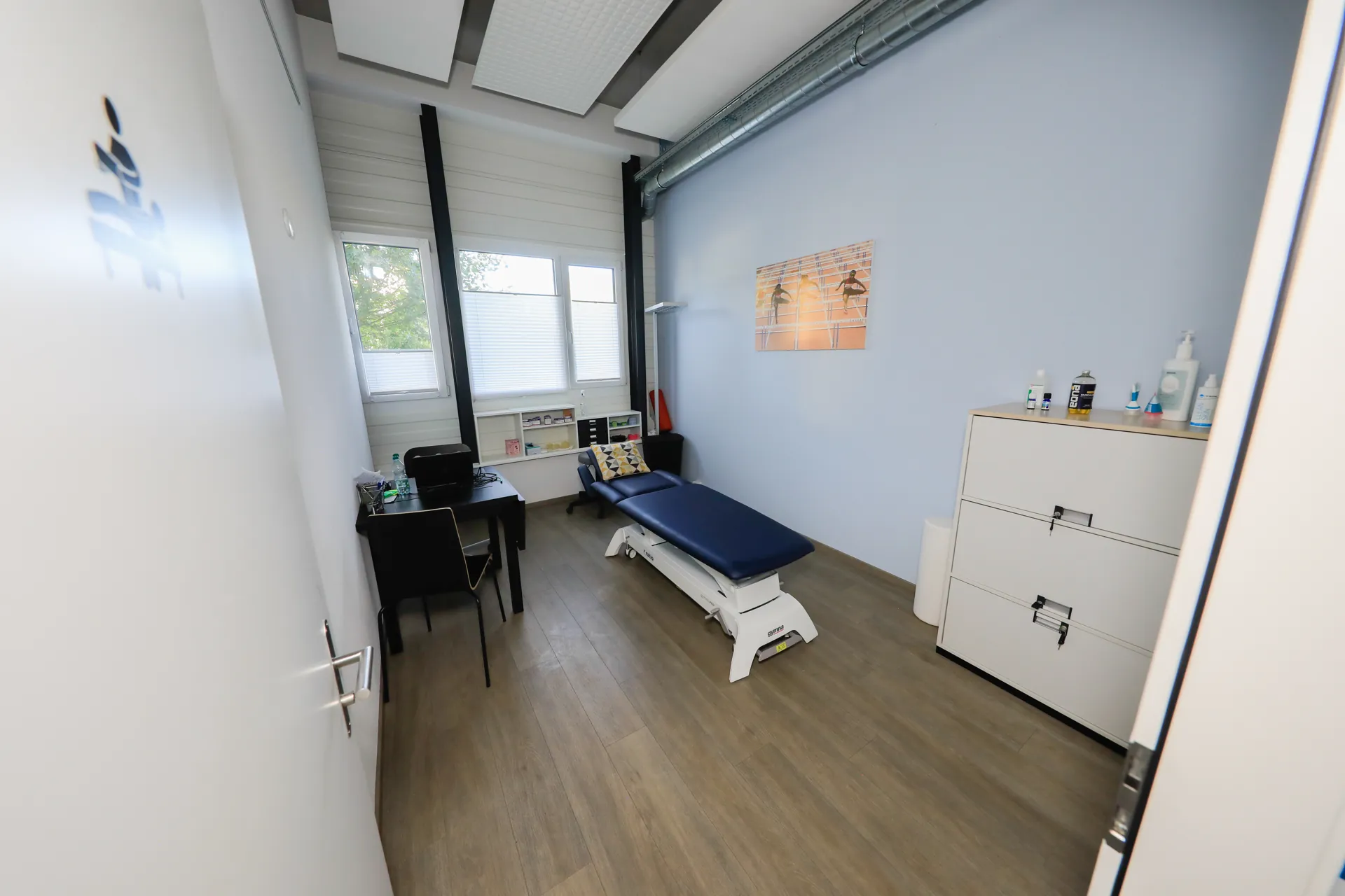 Cabinet de physiothérapie du centre VO2Sport avec table de soin bleue, bureau et armoire de rangement