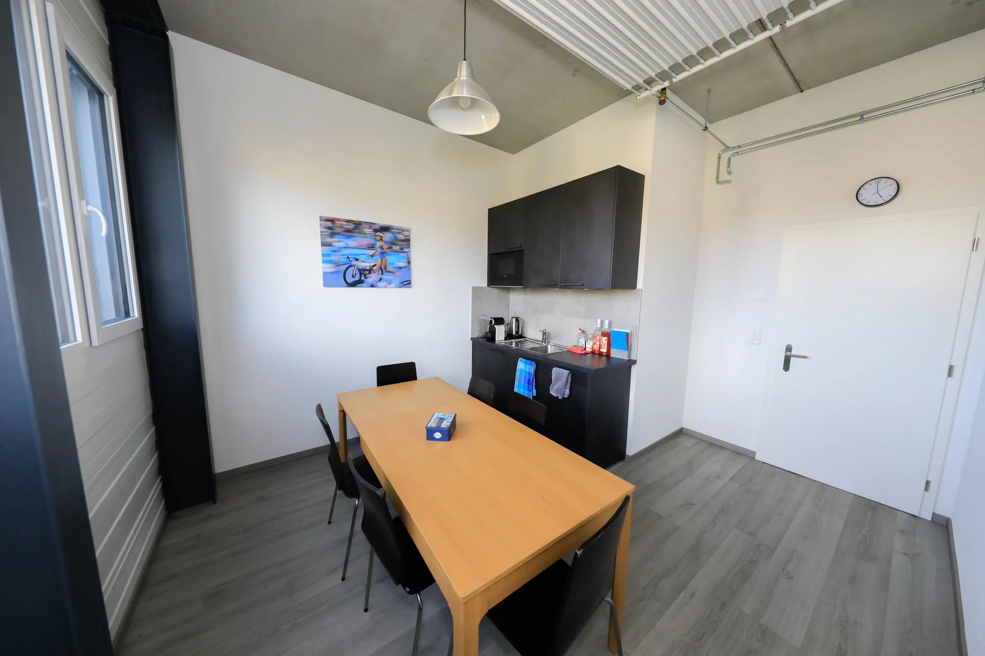 Espace pause du centre VO2Sport avec une table, des chaises et une kitchenette équipée