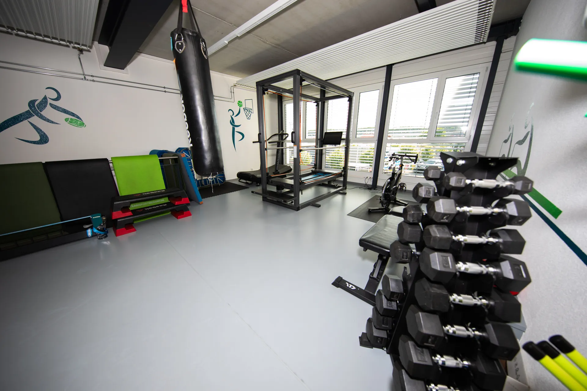 Salle d’entraînement du centre VO2Sport avec haltères, sac de frappe, vélo et appareil de Pilates reformer